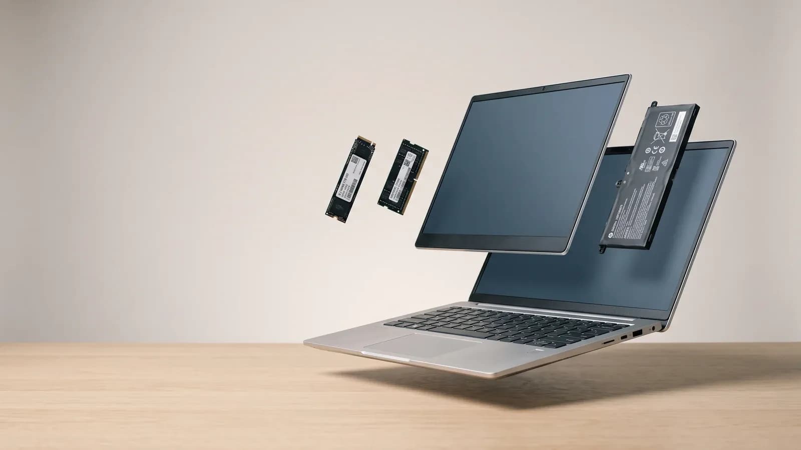 PC portable en vue éclatée avec barrette de RAM, SSD, batterie et dalle d'écran flottant au-dessus du châssis