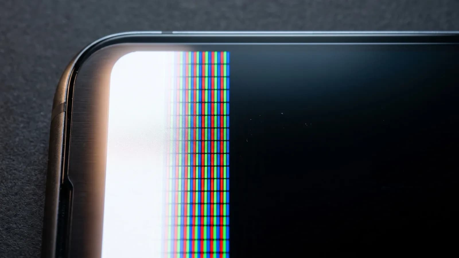 Macro d'un écran de smartphone OLED coupé en deux, sous-pixels rouges verts bleus allumés côté mode clair, noir éteint côté mode sombre