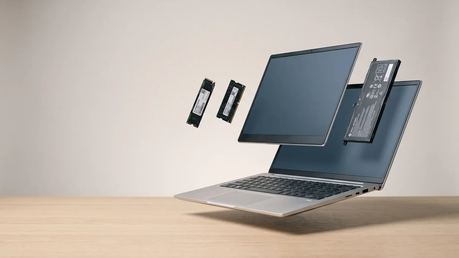 PC portable en vue éclatée avec barrette de RAM, SSD, batterie et dalle d'écran flottant au-dessus du châssis